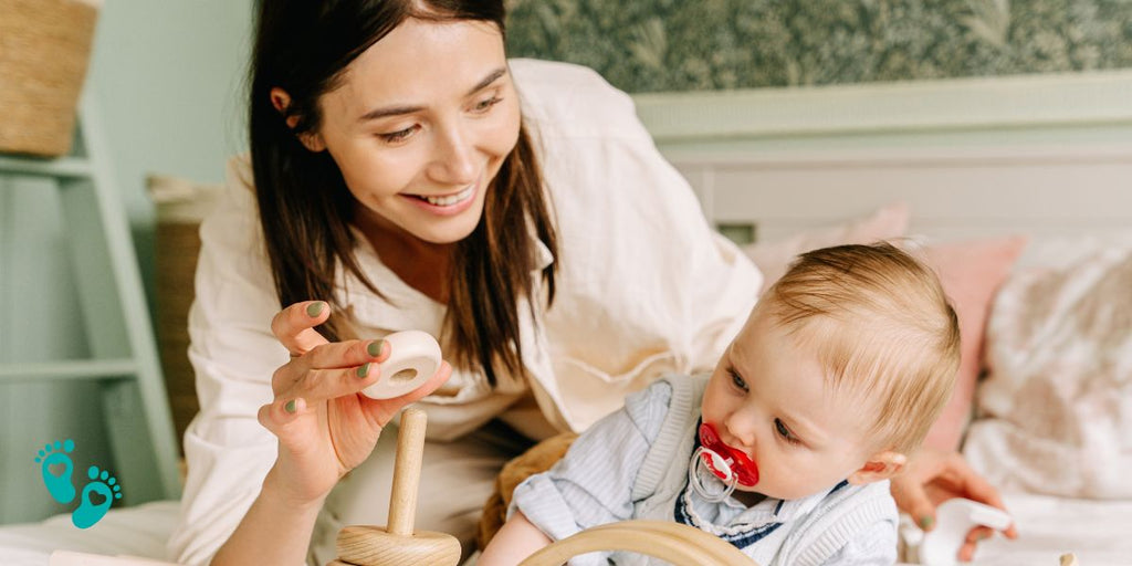 Mother playing with her baby wearing a pacifier, both enjoying quality time, showcasing Grookz baby shoes