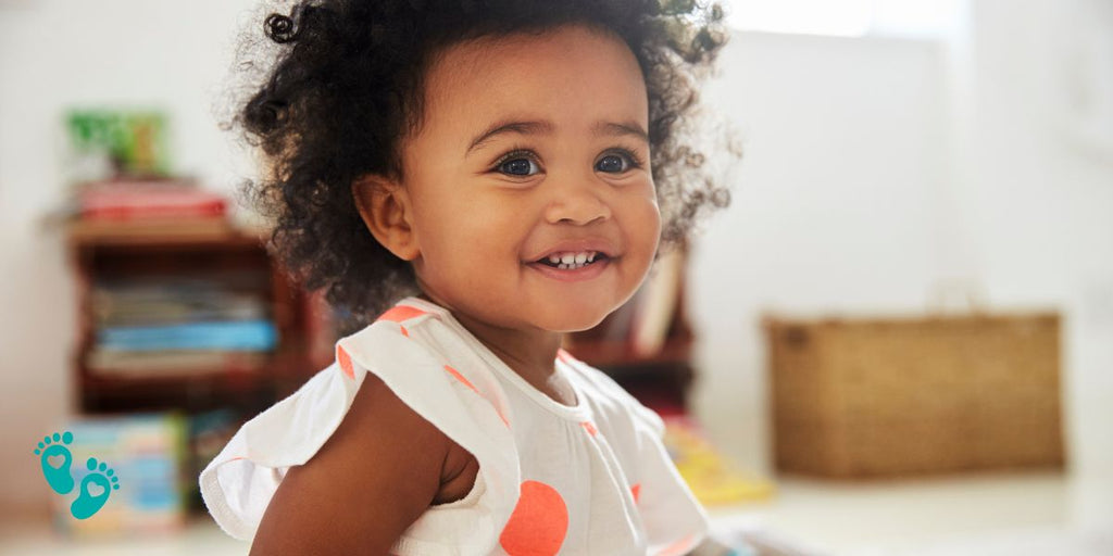 Smiling toddler in a white dress with orange polka dots, ideal for Grookz baby shoes