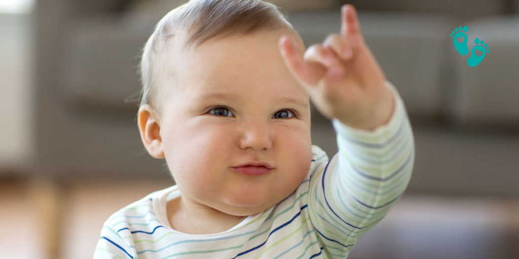 Smiling baby boy pointing while wearing Grookz baby sock shoes for boys.