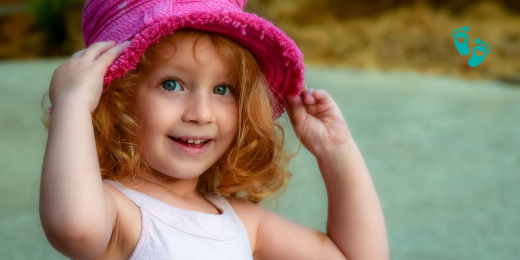 Happy girl wearing a pink hat and Grookz baby sock shoes for girls.