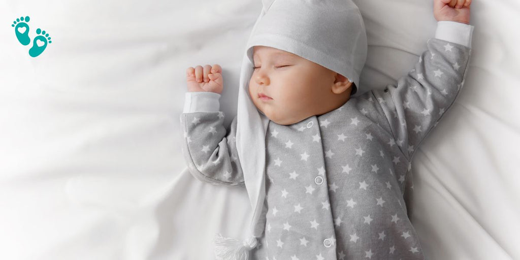 Sleeping baby in a gray star-patterned onesie and hat, showcasing the comfort and coziness of Grookz baby shoes