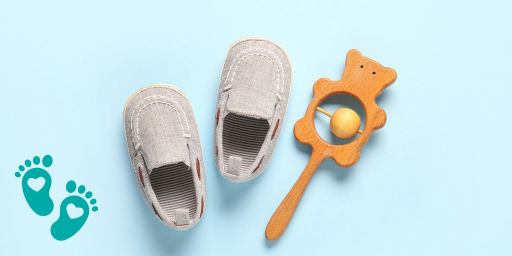 Pair of baby shoes and a wooden rattle on a light blue background, providing an essential guide to choosing the best baby shoes, embracing comfort and style with Grookz