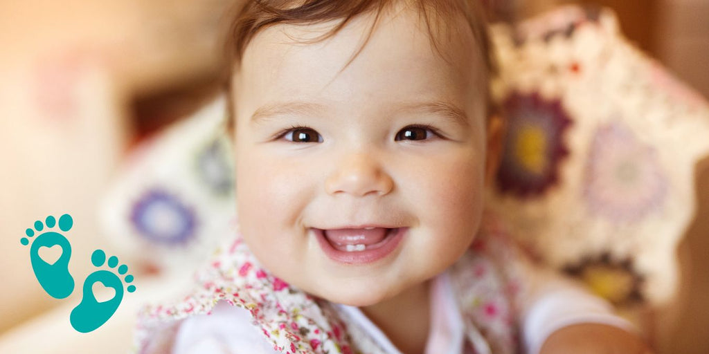 Smiling baby with a colorful blanket, providing a guide to understanding the infant shoe size chart by age with Grookz Shoes