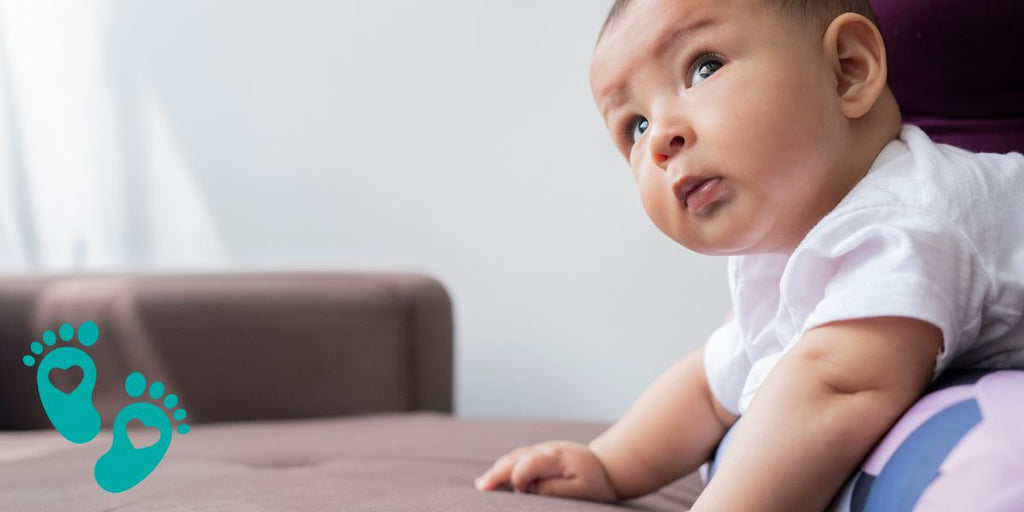 Curious baby looking up while lying on a bed, providing a guide to mastering baby registries with Grookz Shoes for new parents