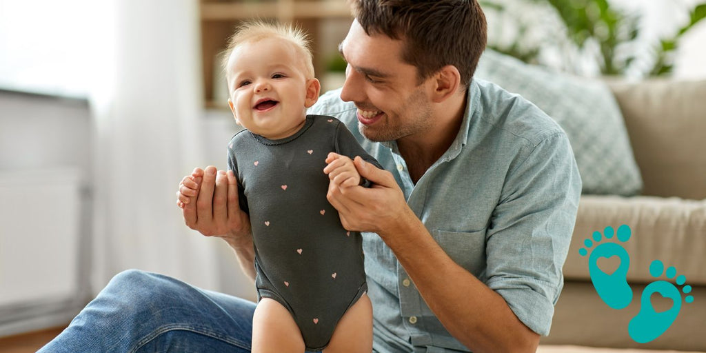 Father holding and playing with his smiling baby, explaining why Grookz's baby sock shoes are the best choice over Amazon's selection