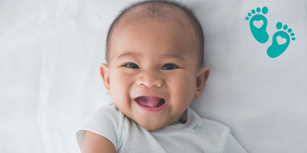 Smiling baby lying on a white blanket, promoting Grookz as the ultimate baby sock shoes with rubber sole for comfort and safety