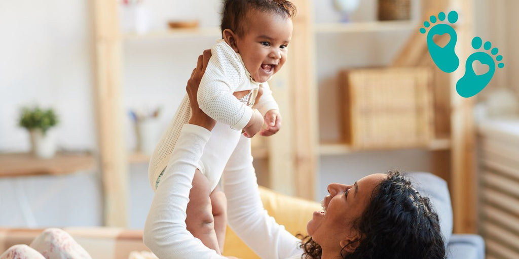 Mother lifting her smiling baby in the air, providing a comprehensive baby shoe guide on when, why, and which shoes to choose with Grookz Shoes