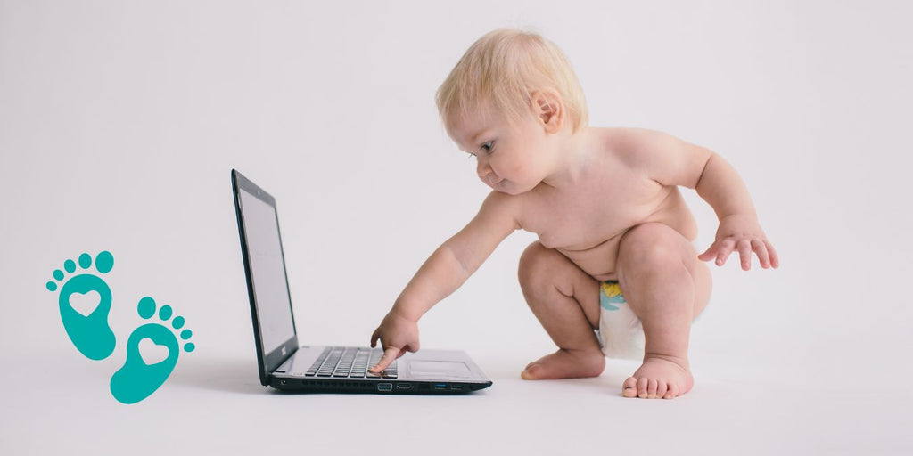 Curious baby playing with a laptop, emphasizing a deep dive into Grookz baby sock shoes for comfort and style