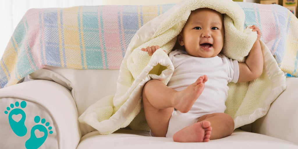 Happy baby sitting on a chair under a blanket, illustrating the ultimate guide to choosing the right Grookz baby shoes