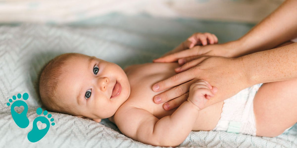 Smiling baby lying on a bed while being gently touched by a parent, exploring why baby shoes are important with Grookz Shoes