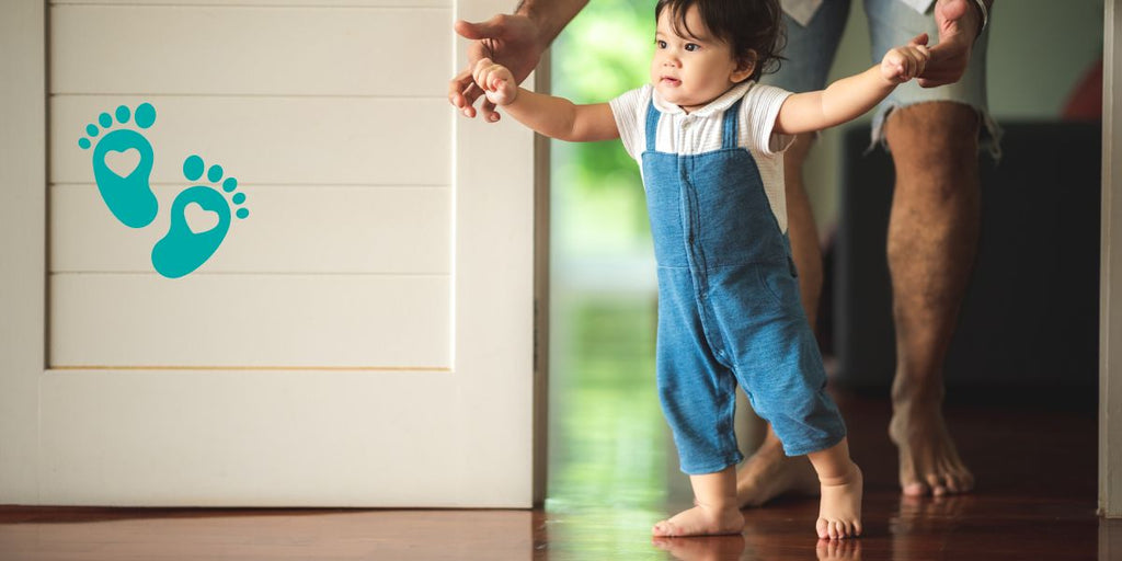 Baby taking first steps while being supported by parent, highlighting foot development milestones with Grookz baby shoes