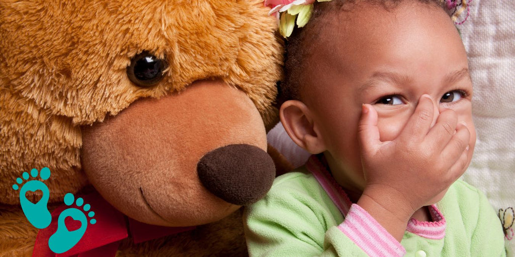 Smiling toddler with a teddy bear, highlighting Grookz baby shoes for playtime and parties 