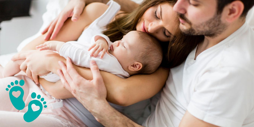 Parents lovingly holding their sleeping baby, discussing the rise of baby sock shoes with rubber soles and the safety and comfort offered by Grookz Shoes